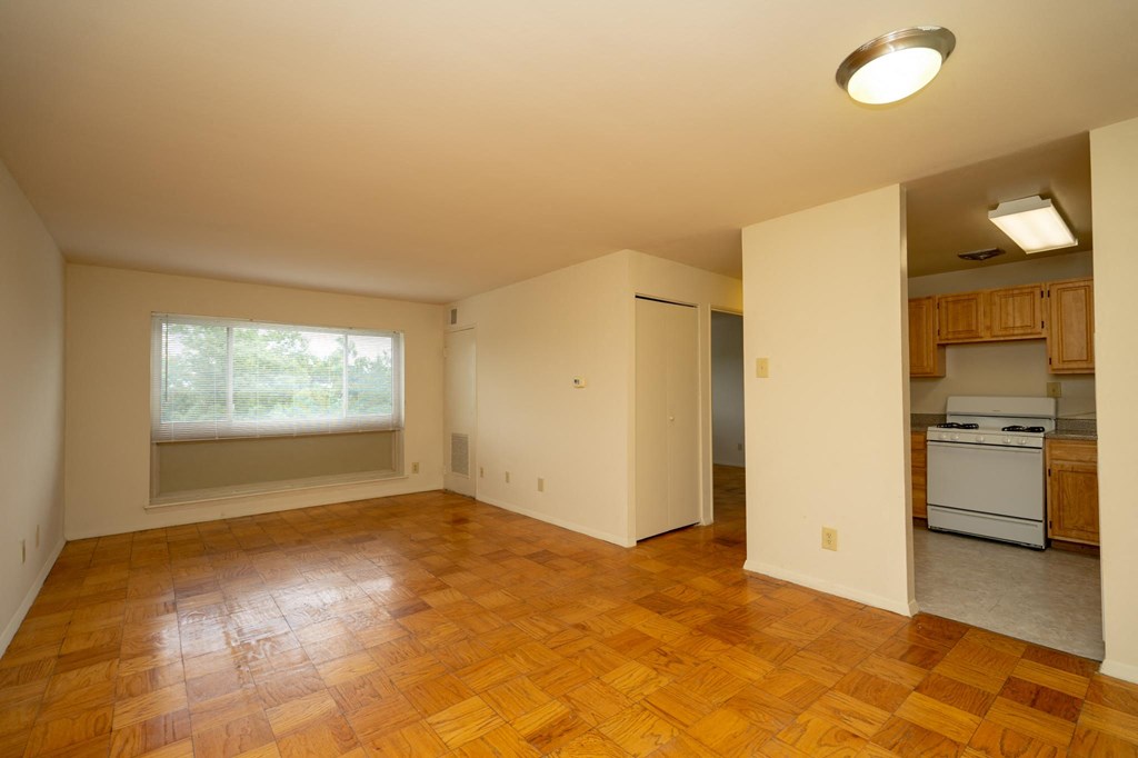 an empty living room and kitchen with wood flooring and a window