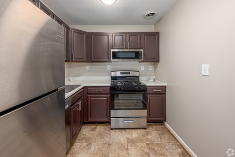 A kitchen with brown cabinets and a stainless steel refrigerator.