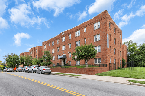 A red brick building with a black fence in front.