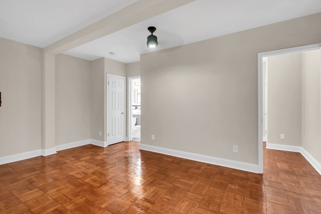 an empty living room with wood flooring and a ceiling light