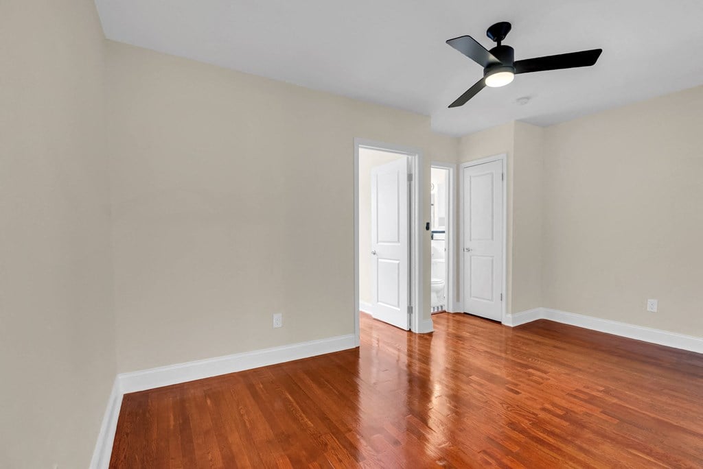 an empty living room with wood floors and a ceiling fan