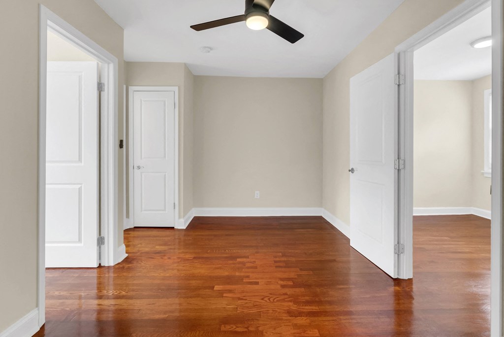 an empty living room with wood floors and a ceiling fan