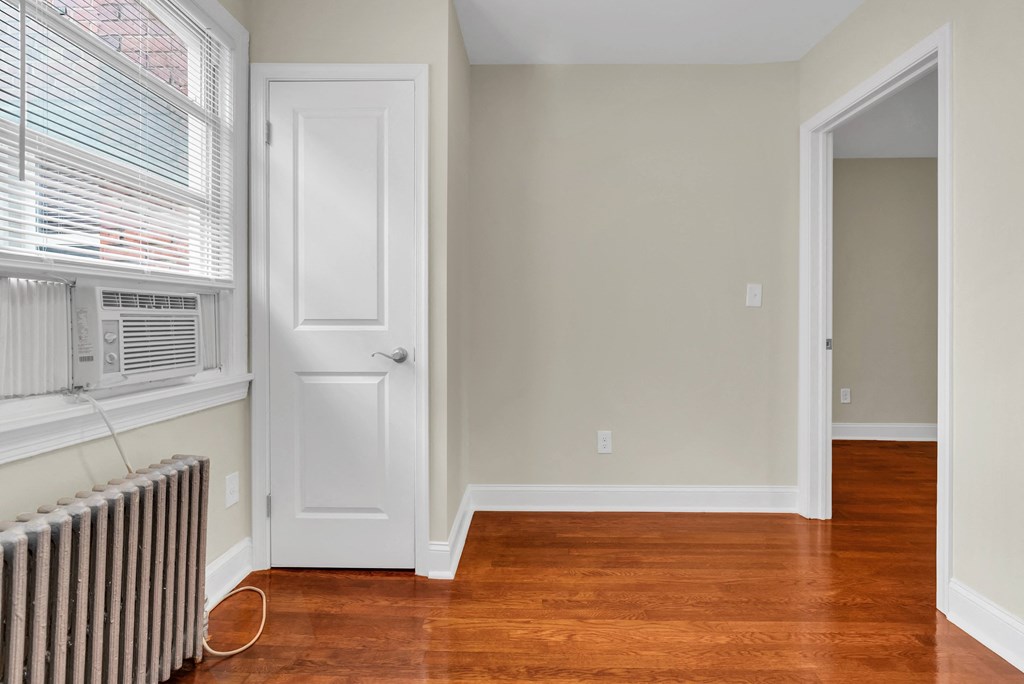 a living room with wood floors and a radiator and a white door