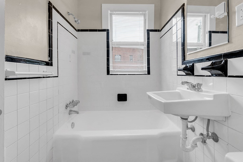 a white bathroom with a sink and a tub and a window