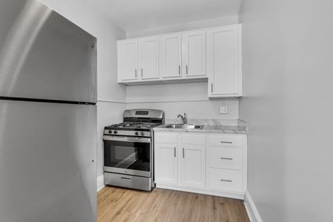 A kitchen with a stainless steel refrigerator, stove, and white cabinets.