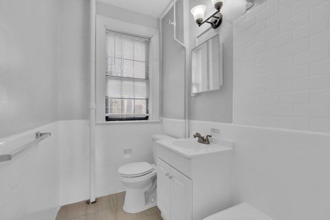 A white bathroom with a toilet, sink, and window.