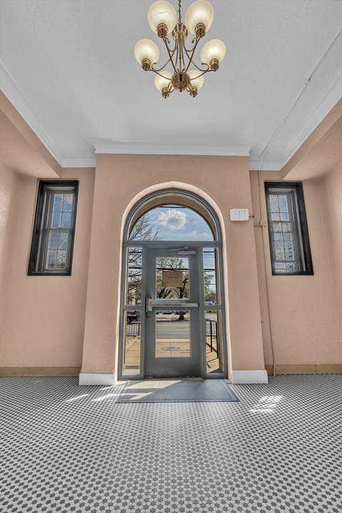 A hallway with a checkered floor and a chandelier.