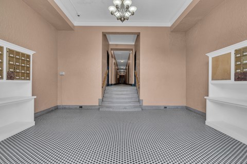 A hallway with a chandelier, stairs, and a wall of mailboxes.