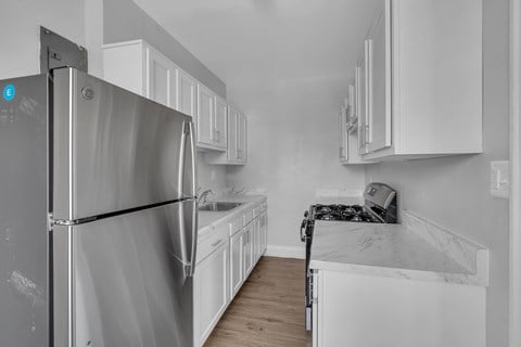 A kitchen with white cabinets and a stainless steel refrigerator.