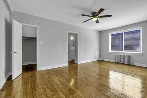 an empty living room with wood floors and a ceiling fan