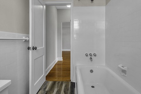 a white bathroom with a tub and a white door