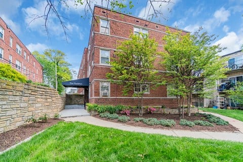 exterior view of a brick building with green grass and trees