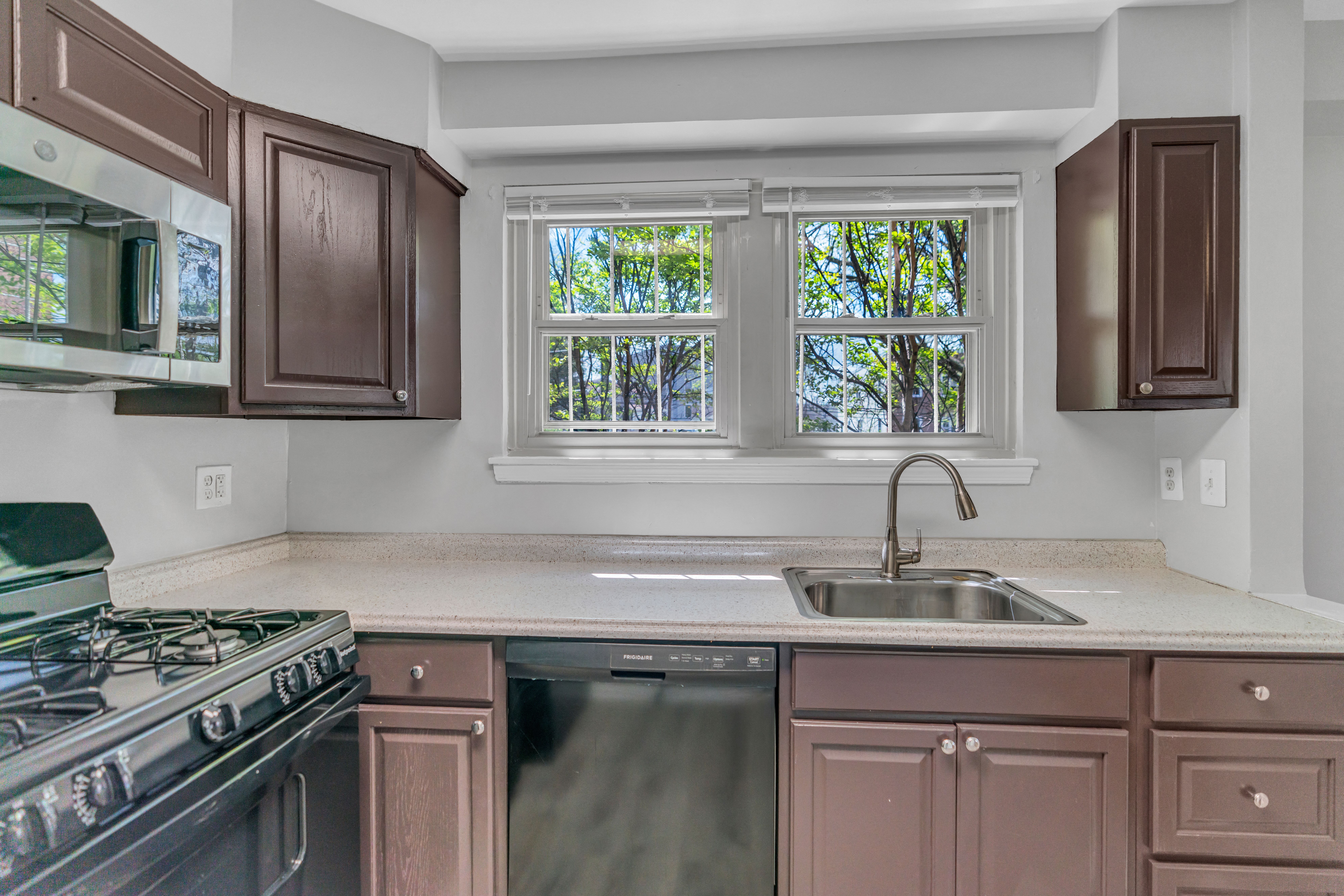 A kitchen with brown cabinets and a black stove top oven.