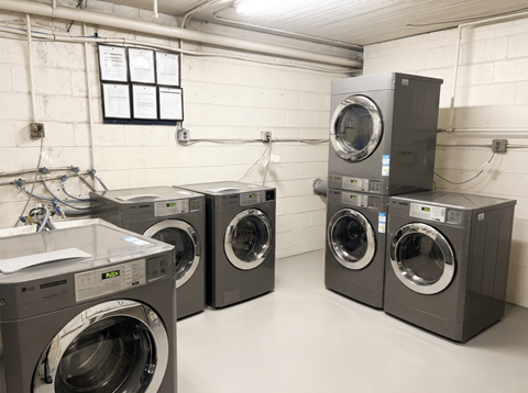 A row of industrial washing machines in a laundry room.
