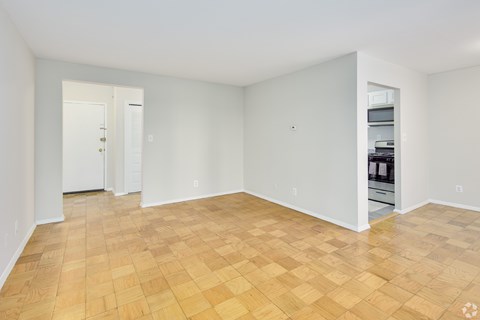 Empty room with wooden flooring and white walls.