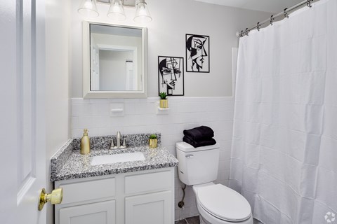 A white bathroom with a toilet, sink, and shower.