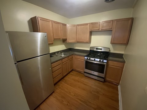A kitchen with wooden cabinets and a stainless steel refrigerator.