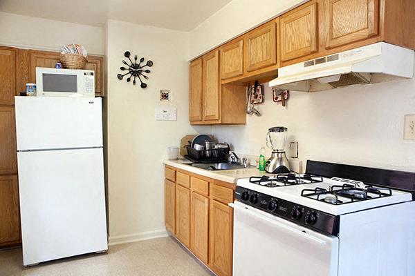 A kitchen with a white fridge, white stove, and wooden cabinets.