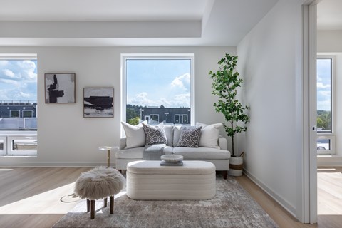 A living room with a white couch, a small table, and a large window.