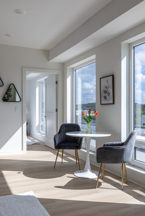 A dining room with a white table and two black chairs.