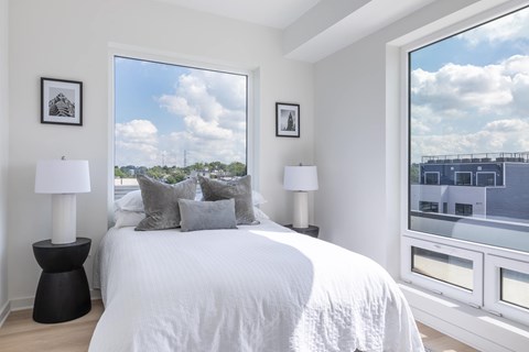 A bedroom with a large bed, two lamps, and pictures on the wall.
