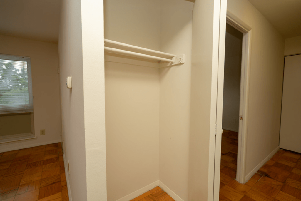 an empty closet in a room with wood floors and a window