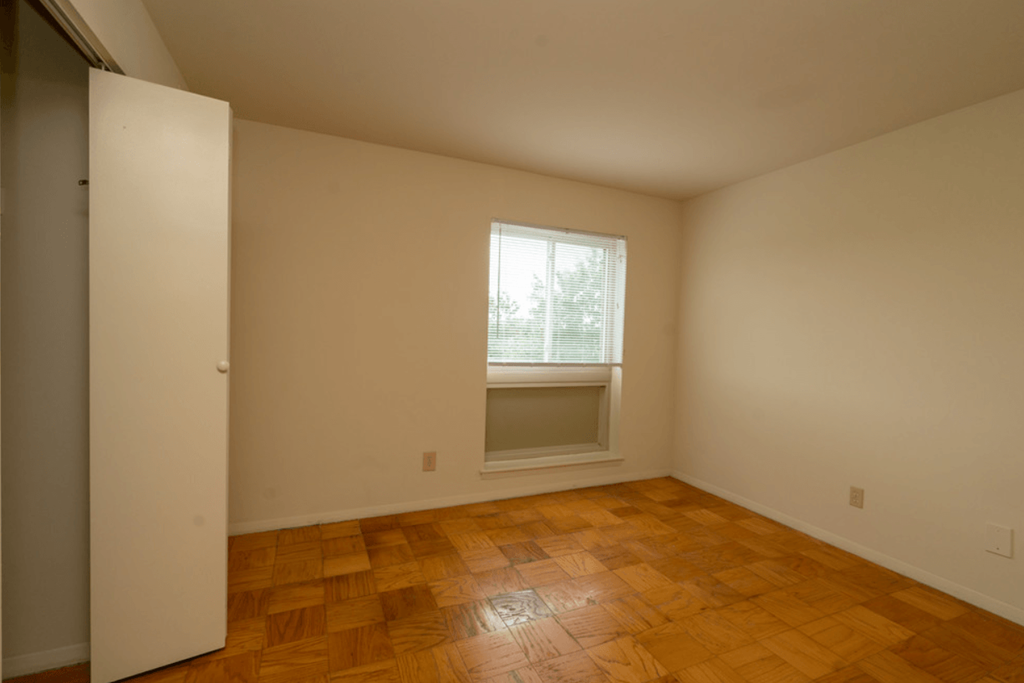the living room of an empty house with a window and wooden floors