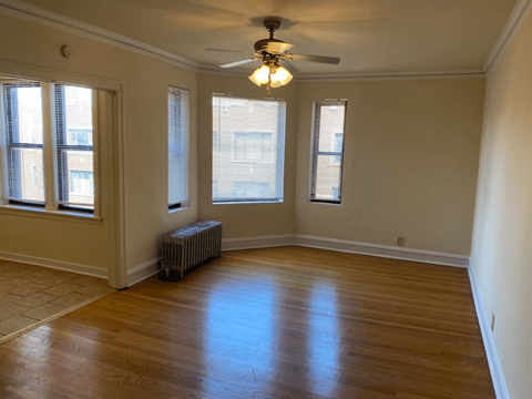an empty living room with a ceiling fan and three windows
