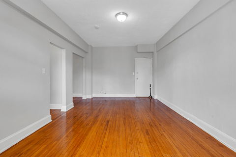 an empty living room with wood floors and white walls