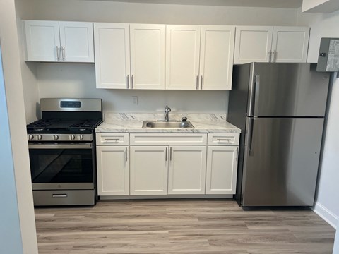 A kitchen with white cabinets and a stainless steel refrigerator.