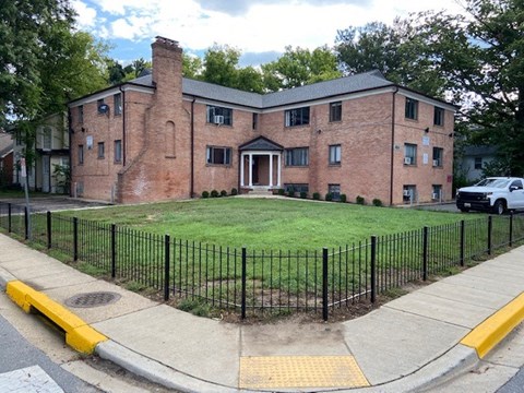 A brick building with a black fence and a yellow curb.