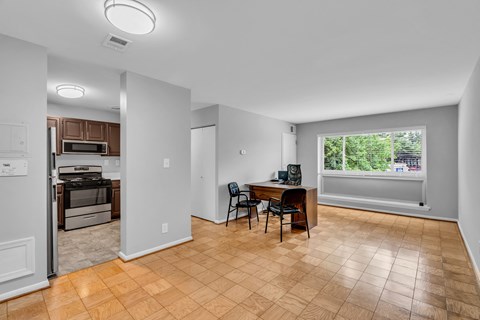 an empty living room with a kitchen and a table with chairs