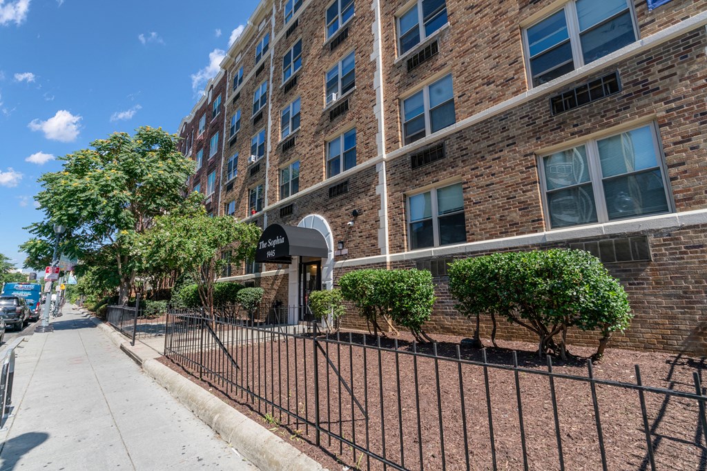 an apartment building with a gate and a sidewalk in front of it