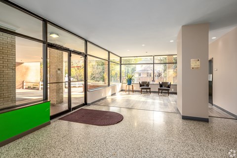 A hallway with a green wall and a red rug.