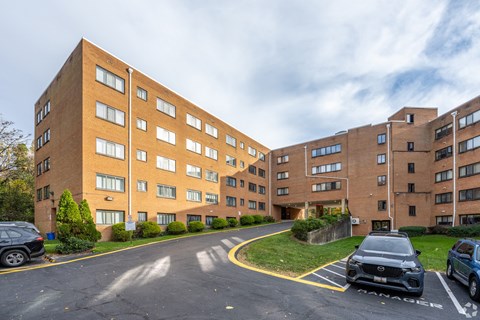 A parking lot in front of a brick apartment building.