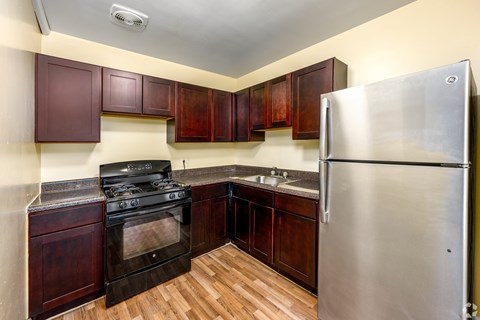 A kitchen with a stove, sink, and refrigerator.