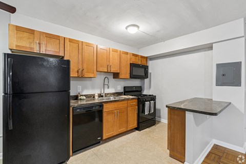 A kitchen with black appliances and wooden cabinets.