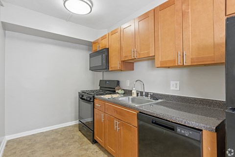 A kitchen with wooden cabinets and black appliances.