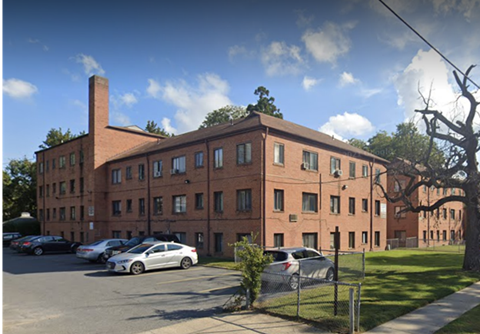 A red brick building with a parking lot in front.