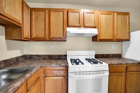 A white gas stove in a kitchen with wooden cabinets.