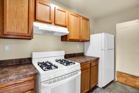 A white stove is in a kitchen with wooden cabinets.