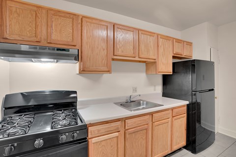 A kitchen with wooden cabinets and a black refrigerator.