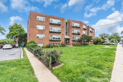 A red brick apartment building with a green lawn in front.
