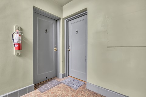 A hallway with two doors and a fire extinguisher on the wall.