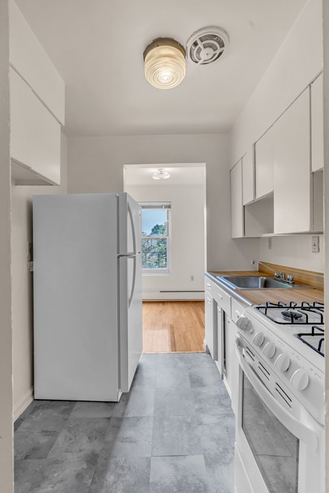 A white kitchen with a large refrigerator and a stove top oven.