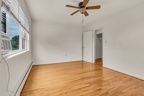 A room with a ceiling fan and wooden flooring.