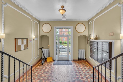 A hallway with a tiled floor and a black railing.