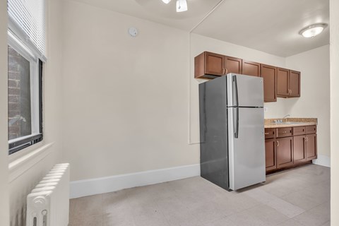 A kitchen with a refrigerator and brown cabinets.