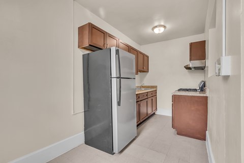A kitchen with a refrigerator, sink, and cabinets.