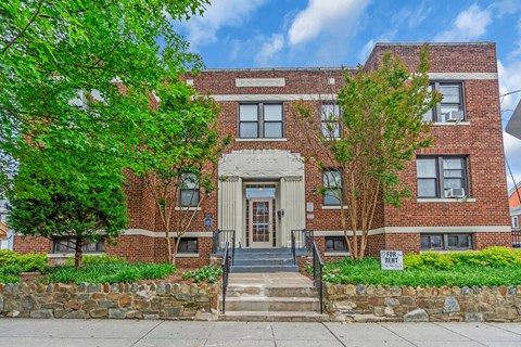 A red brick building with a stone wall in front.